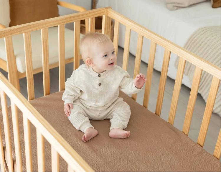 Baby resting comfortably in a cozy crib with a soft, breathable KeaBabies crib sheet.
