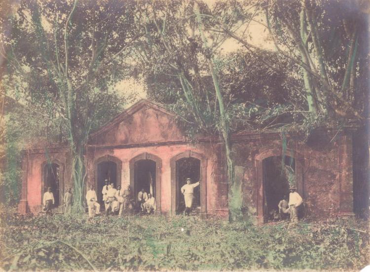 Foto colorida que mostra diversas pessoas em pé diante de construção, rodeada por árvores. Alfredo Clímaco de Carvalho. O Almirante José Carlos de Carvalho, o Dr. Octavio Costa Marques e grupo em visita ao Forte do Príncipe da Beira, 6/07/1913. Costa Marques, Rondônia / Acervo DPHDM