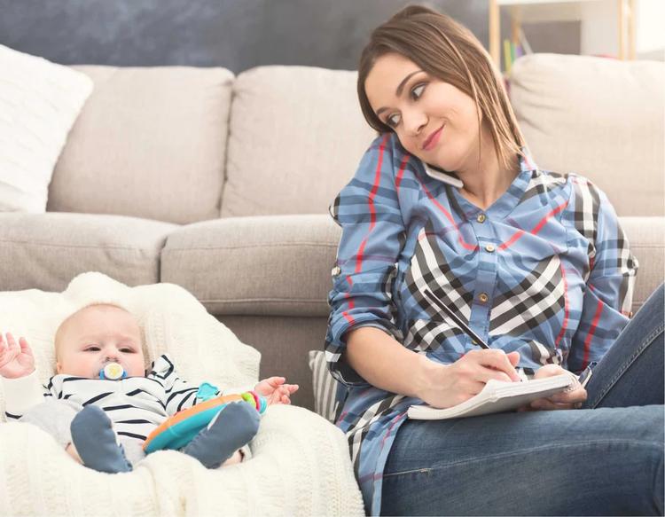 A mom making a family travel checklist and planning essentials for a road trip with her baby.