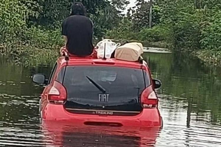 Motorista sobe em teto de carro após ficar ilhado durante enchente no litoral de SP