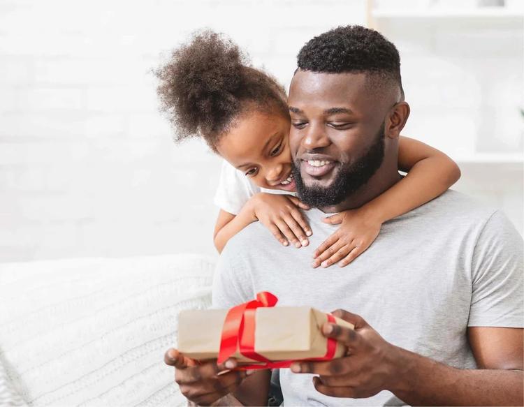Toddler giving a Father’s Day gift to his dad during a sweet family moment.