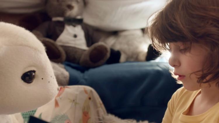 a child reads a book to familiar machines & magic robot companion ami