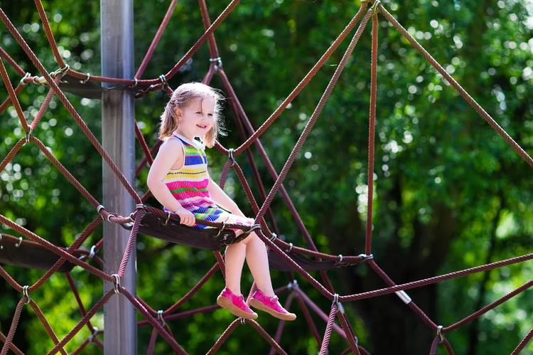 Toddler playing outdoors at a sunny playground during active playtime.