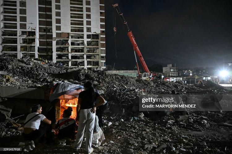 Venezuelans light candles amid the rubble of a collapsed building from the state-run OPP housing blocks two months after the 7.2 and 7.5-magnitude earthquakes in La Guaira, Venezuela on August 24, 2026. The magnitude 7.2 and 7.5 tremors on June 24, 2026, devastated the coastal state of La Guaira, where at least 190 buildings fell apart. Venezuela's interim government reported 6,509 deaths on August 24, 2026, exactly two months after the twin earthquakes.