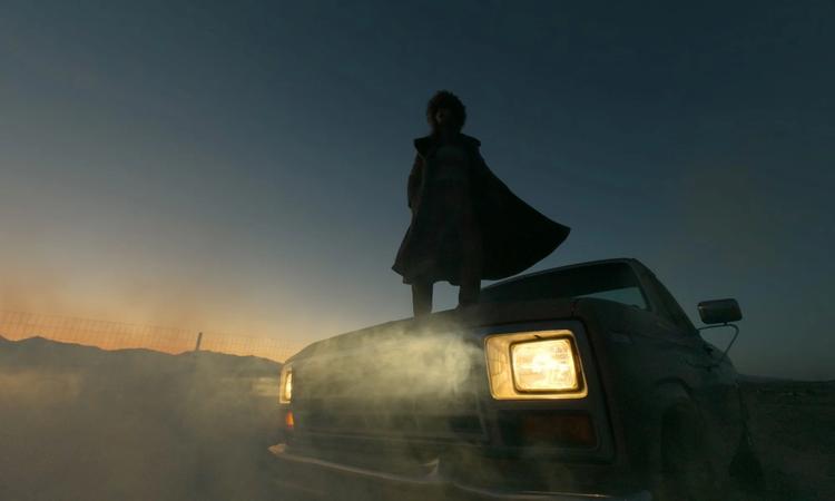 a woman standing on a truck hood at sunrise