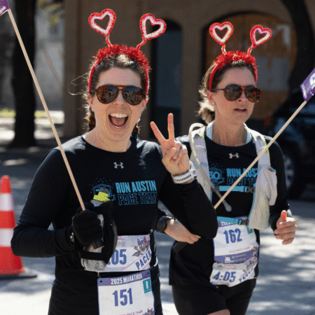 Two women running the Austin Marathon, wearing black
