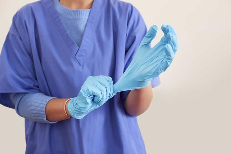 Sterile processing professional putting on gloves before starting work.
