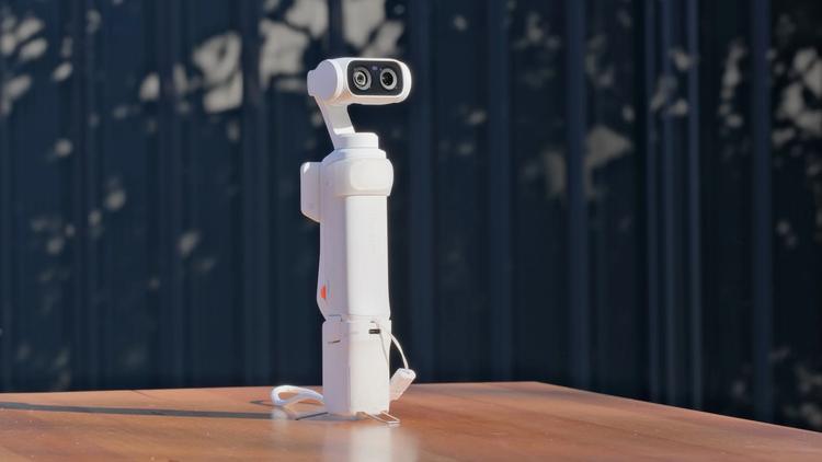 The Insta360 Luna Ultra with its battery handle attached and tripod feet deployed.