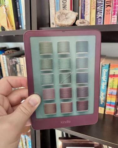 kindle colorsoft held in front of a bookshelf