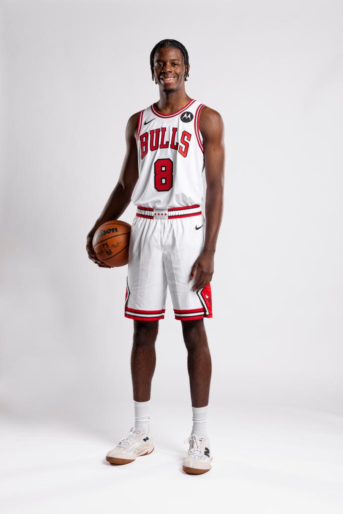 Caleb Wilson, earing his Chicago Bulls uniform, holds a basketball and smiles for a photo shoot.