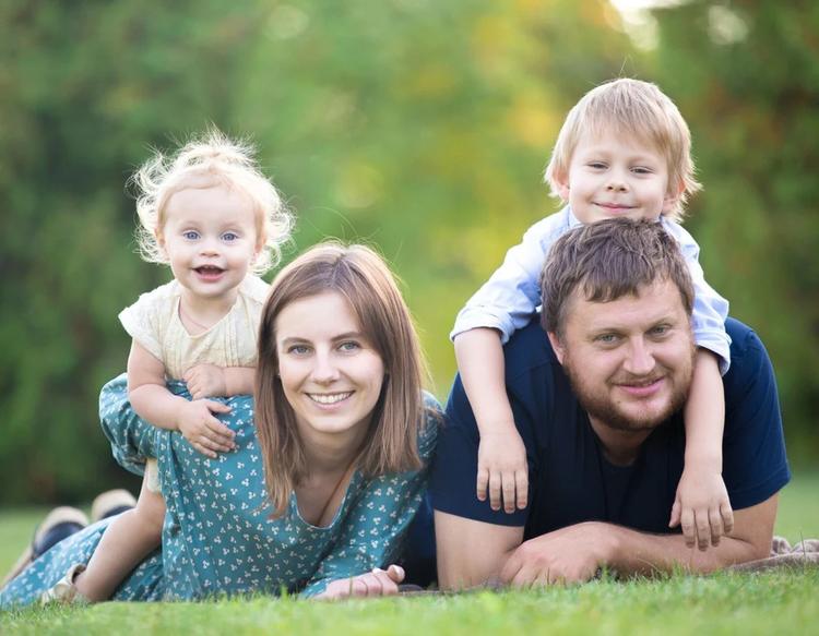 Happy couple with two young children enjoying a sunny day at a grassy park.