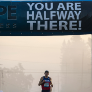 A runner in a race passes under a large banner that reads 