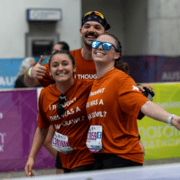 Three runners from a local running crew pose at the finish line in matching orange t-shirts that read, “I thought this was a bar crawl?”. Austin Marathon Half Marathon & 5K