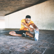 Smiling man stretching under concrete overpass