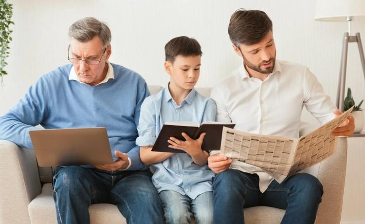 Famiglia maschile che utilizza computer portatile, leggendo libri e giornali a casa