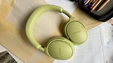 green bose headphones on pile of papers next to colored pencils