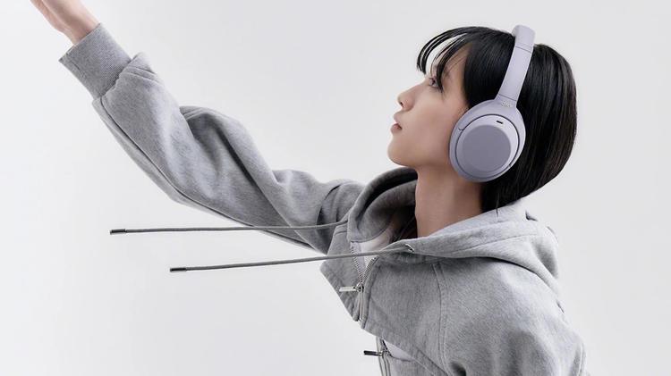 person wearing purple sony headphones reaching their arm out