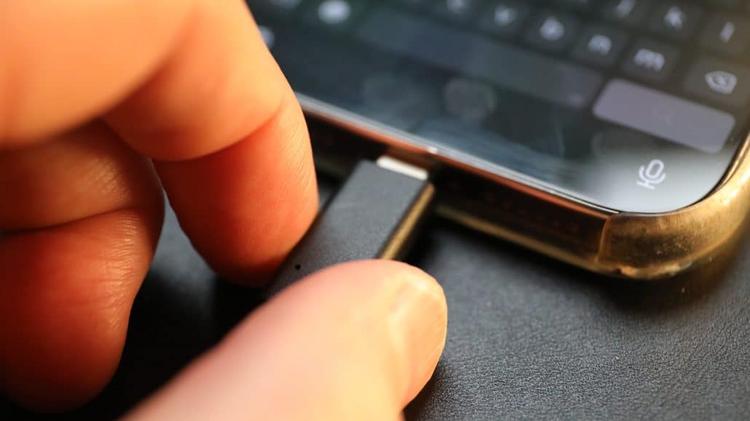 Hand steckt Ladekabel ins Smartphone