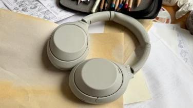 silver sony headphones on pile of papers next to colored pencils
