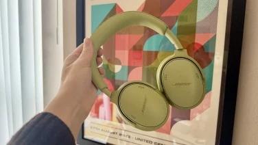 person holding green bose headphones in front of picture