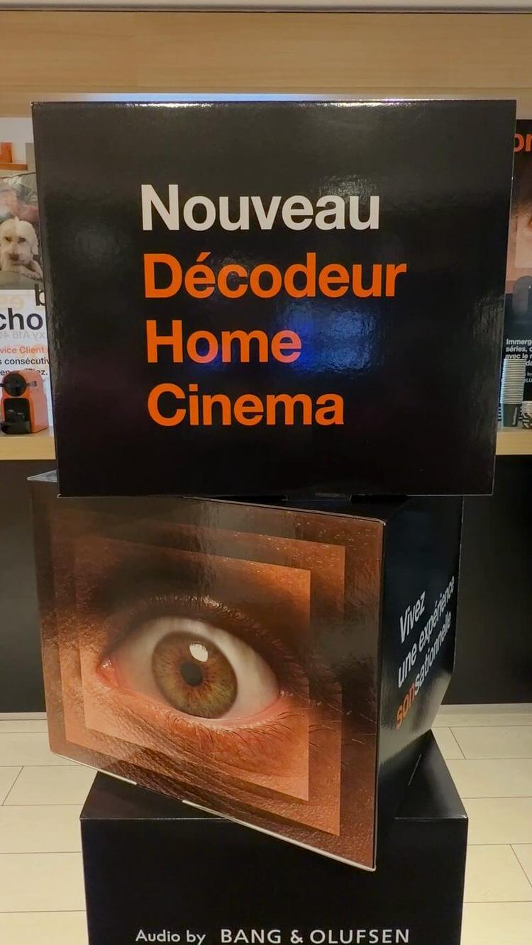 Totem noir et orange « Nouveau Décodeur Home Cinema » avec un grand œil, dans la boutique Orange de Bordeaux