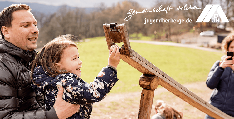  Vater mit seiner Tochter und Mutter fotografiert die beiden im Hintergrund