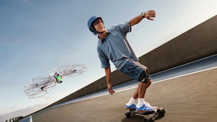 A man skateboarding while wearing the Antigravity A1 Watch Remote and Ring, followed by an A1 drone with Propeller Guards on it.