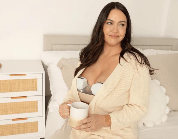 Mom drinking warm water while using KeaBabies Pulse Breast Pump to express milk.