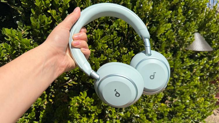 person holding soundcore headphones in front of shrub