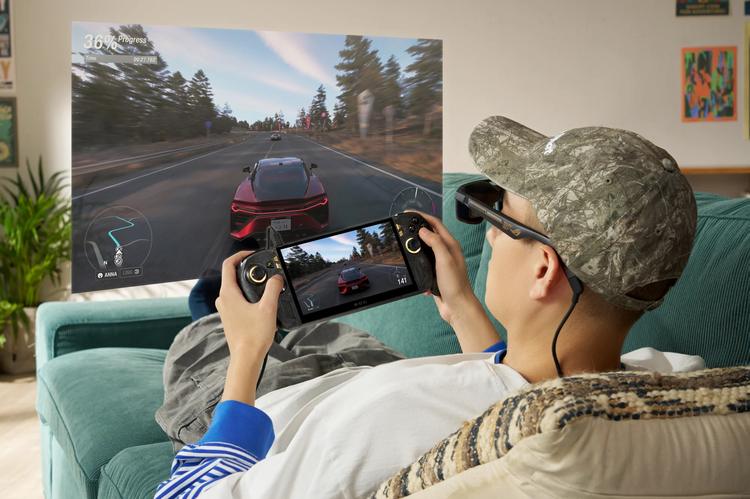 a man playing on the asus rog xbox ally x20 while wearing ar glasses