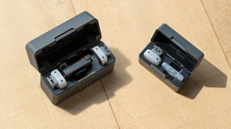 Three DJI Mic Mini 2S transmitters in their charging cases. Two are in a dual case, while one is in an individual case.