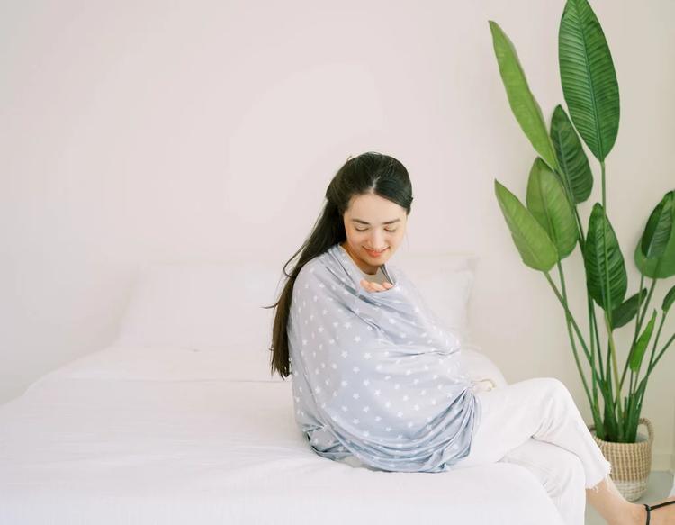 Mom nursing baby using the KeaBabies All-in-1 Multi-Use Cover for privacy and breathable coverage