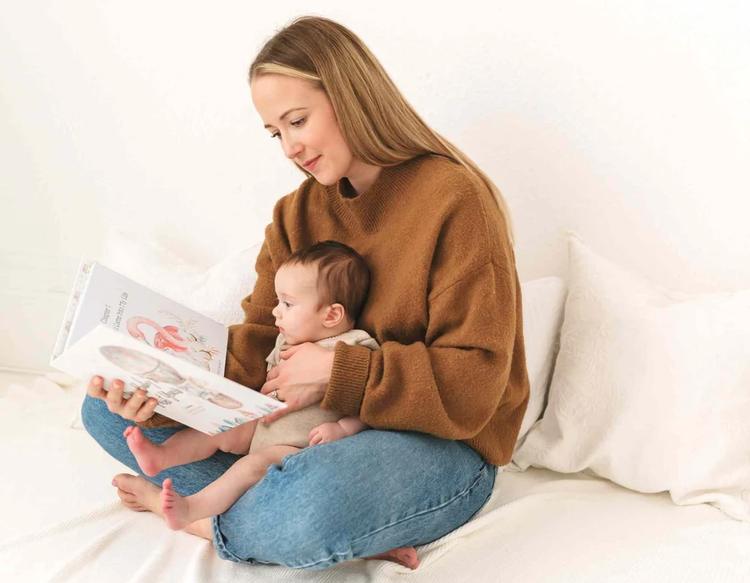 Mom bonding with her baby while looking through a memory book, cherishing and recalling sweet milestones and heartfelt family memories.