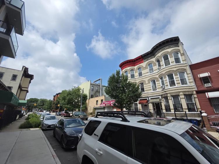 An ultrawide shot of a street in Brooklyn with multi-colored apartment buildings