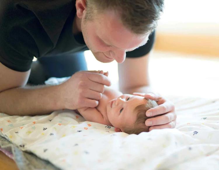 Dad changing his baby’s diaper during a parenting moment at home.