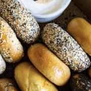 A selection of plain and everything bagels near a small container of cream cheese, perfect for a pre-run carb load. Austin Marathon Half Marathon & 5K