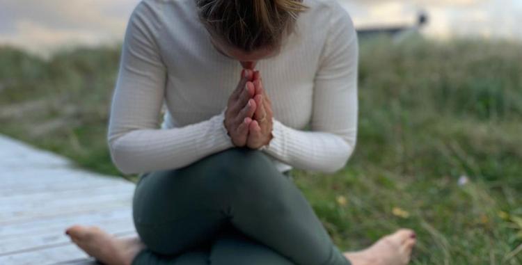  Frau in sitzender Yoga-Position im Gras