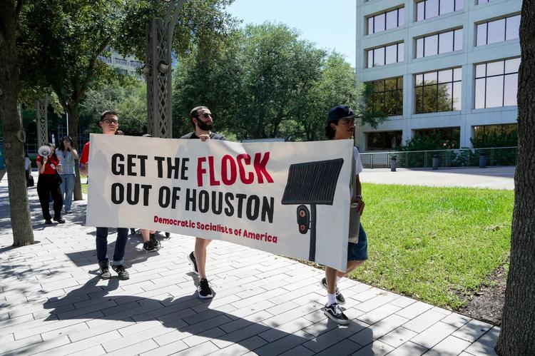 Participants walk near the Gerald D. Hines Waterwall Park, stopping at several Flock Safety cameras along the way during a community walk led by Jasmine Khadem Gonzalez, 27, and organized with Houston DSA and other groups in Houston, Saturday, Aug. 22, 2026.
