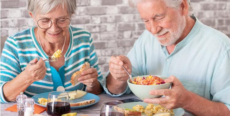  Älteres Ehepaar sitzt am Tisch und frühstückt gemeinsam gesunde Lebensmittel