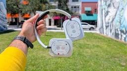 man's hand holding nothing headphon (1) in front of grass