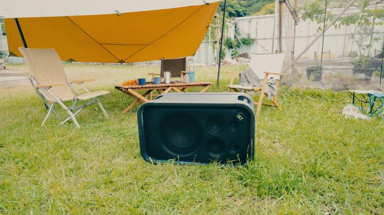 Sony ULT Tower 7 on its side in the grass near a camping setup