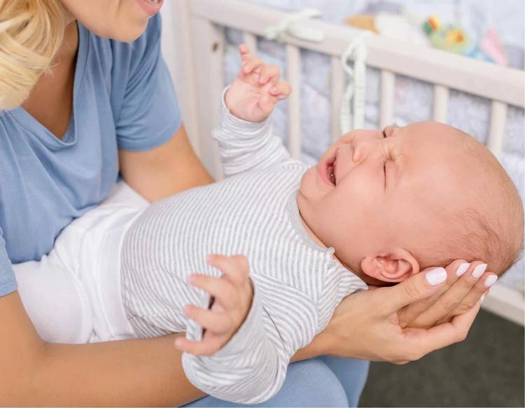 Baby crying in discomfort during the night, highlighting infant sleep problems, teething pain, nighttime wake-ups, and common causes of disrupted baby sleep.