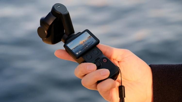 The DJI Osmo Pocket 4P with its screen on, in someone's hand.
