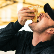 Close-up of man biting pizza slice