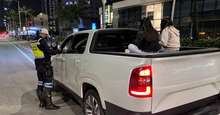 Dupla pega “carona” na caçamba de caminhonete para gravar vídeo e abordagem termina com multa em Balneário Camboriú