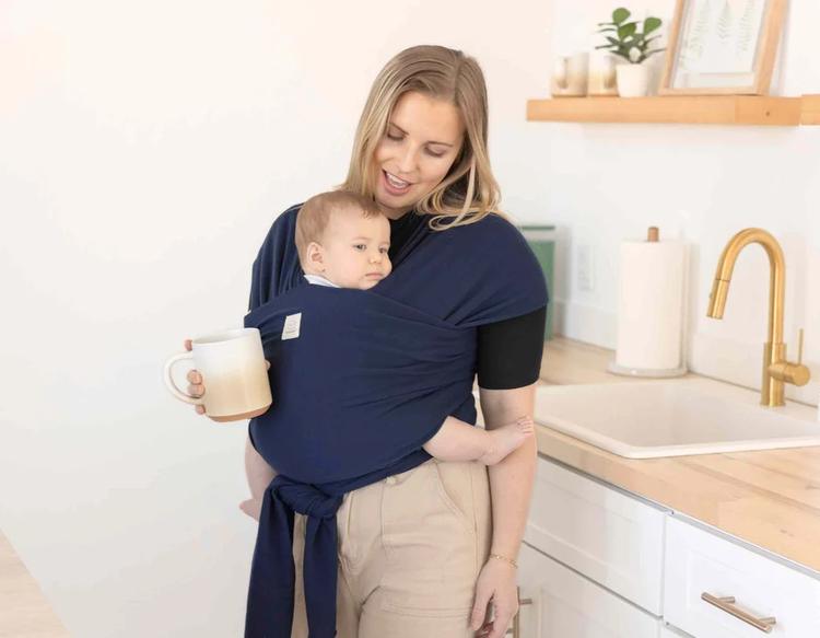 Mom babywearing her infant in a soft wrap carrier, enjoying a hands-free moment for daily tasks and bonding, highlighting a practical solution for new moms.