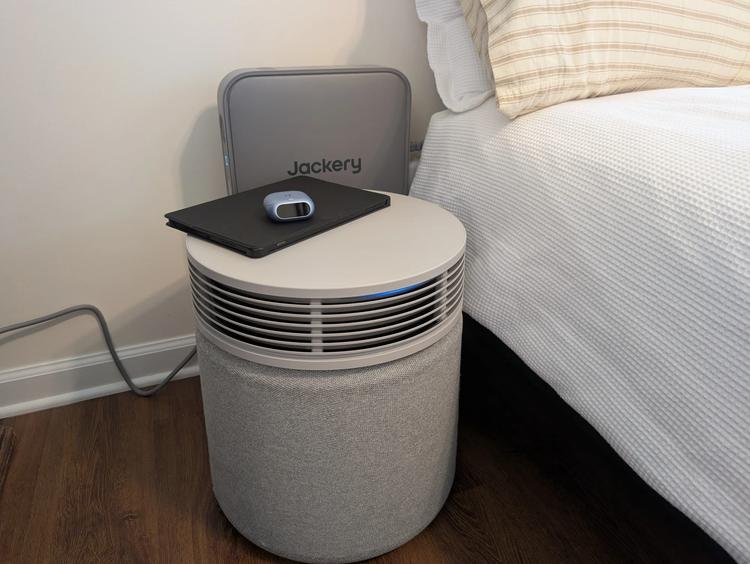 the Jackery FridgeGuard behind an air purifier next to a bed.