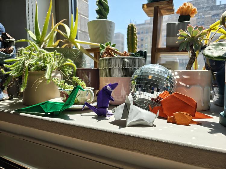 origami models arranged by indoor garden in bright sunlight