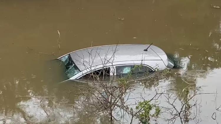 Motorista perde o controle de carro em pista molhada e veículo cai em córrego em Mogi das Cruzes