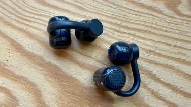 dark grey cmf clip pro earbuds on wood tabletop